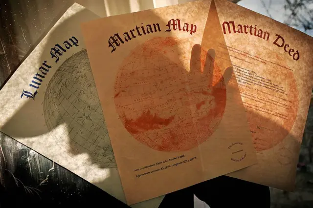 Três papéis com o mapa de imóveis da Lua, de Marte e a escritura de um terreno em Marte